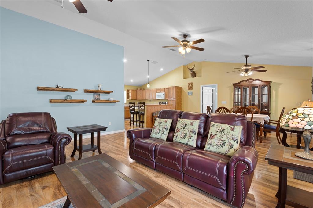 A living room with leather furniture, wood flooring, and an open kitchen in the background — 10250 NE 5TH AVENUE, BRANFORD, FL