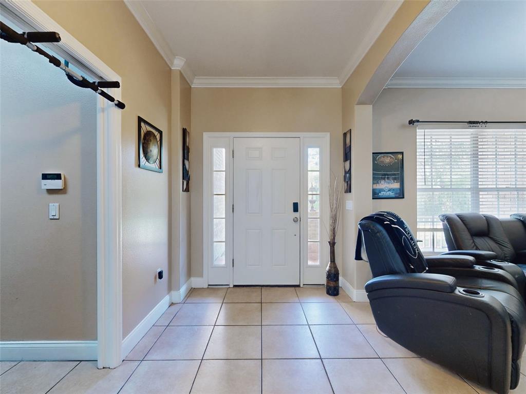 An entryway with tiled floors, a white front door, and a view into a living room — 3040 BUTLER RIDGE ROAD, DELTONA, FL