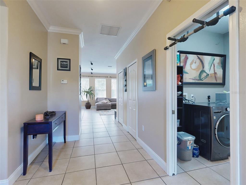 A hallway with tile flooring leads to a living area, with a laundry room adjacent — 3040 BUTLER RIDGE ROAD, DELTONA, FL