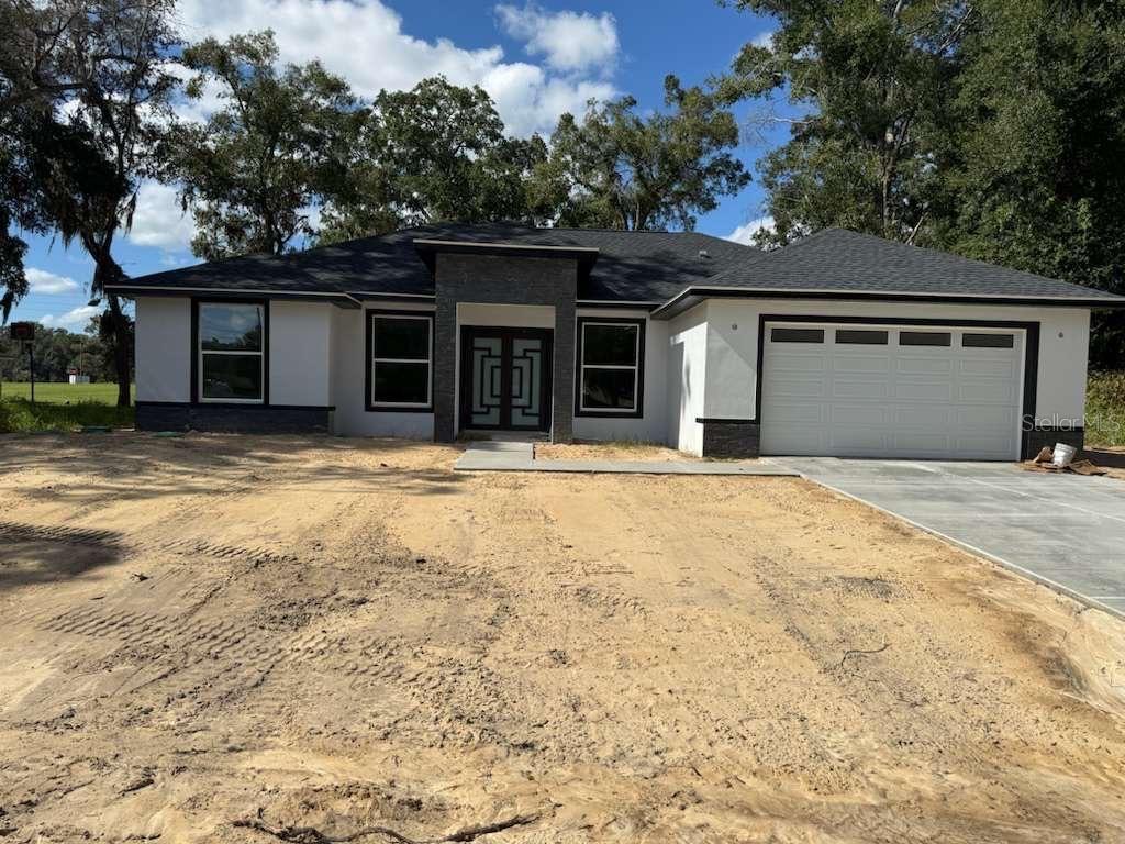 A modern kitchen features gray cabinets, a white quartz island, and white marble-patterned tile flooring — 12320 SE 70TH AVENUE, BELLEVIEW, FL