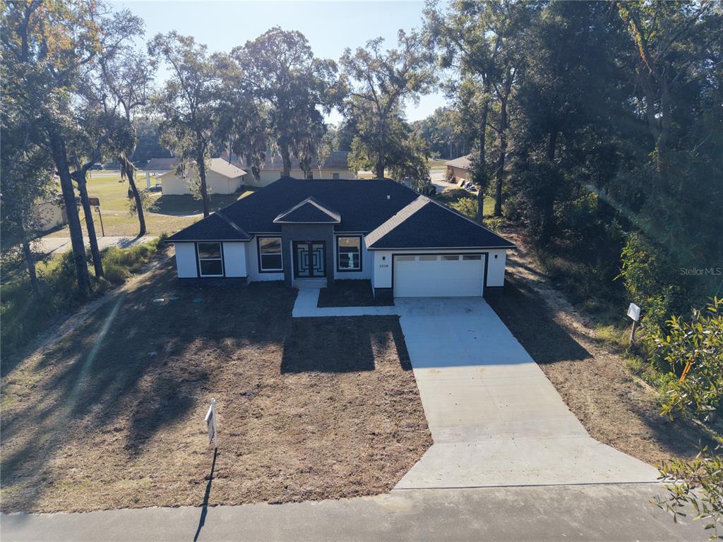 An open-concept kitchen and living area features white marble-look tile flooring and a center island — 12320 SE 70TH AVENUE, BELLEVIEW, FL