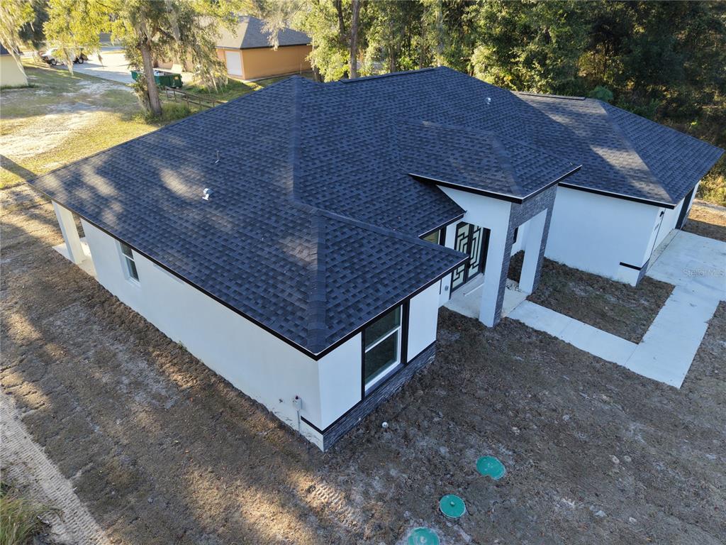 A bright room features white marble-look tile flooring and a modern chandelier near glass doors — 12320 SE 70TH AVENUE, BELLEVIEW, FL