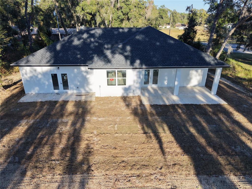 A spacious room features white marble-look tile flooring, a vaulted ceiling, and a modern chandelier — 12320 SE 70TH AVENUE, BELLEVIEW, FL