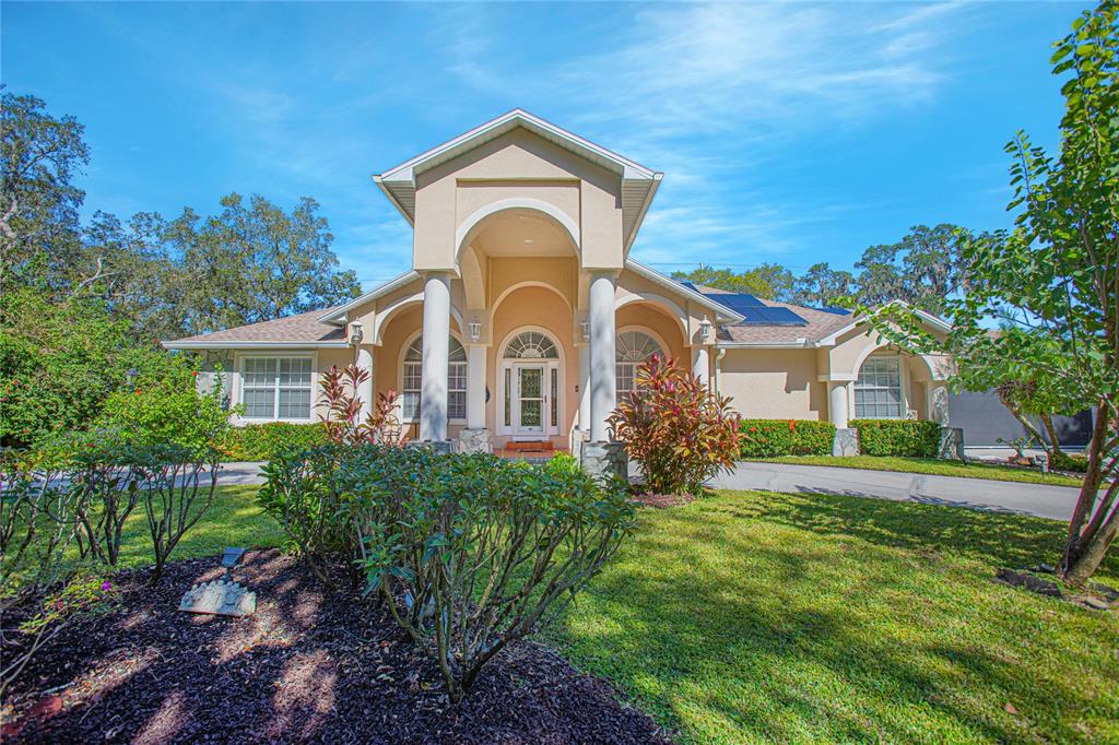 A single-story house with a prominent arched entryway, white columns, and a landscaped front yard — 4735 CHELSEA COURT, KISSIMMEE, FL