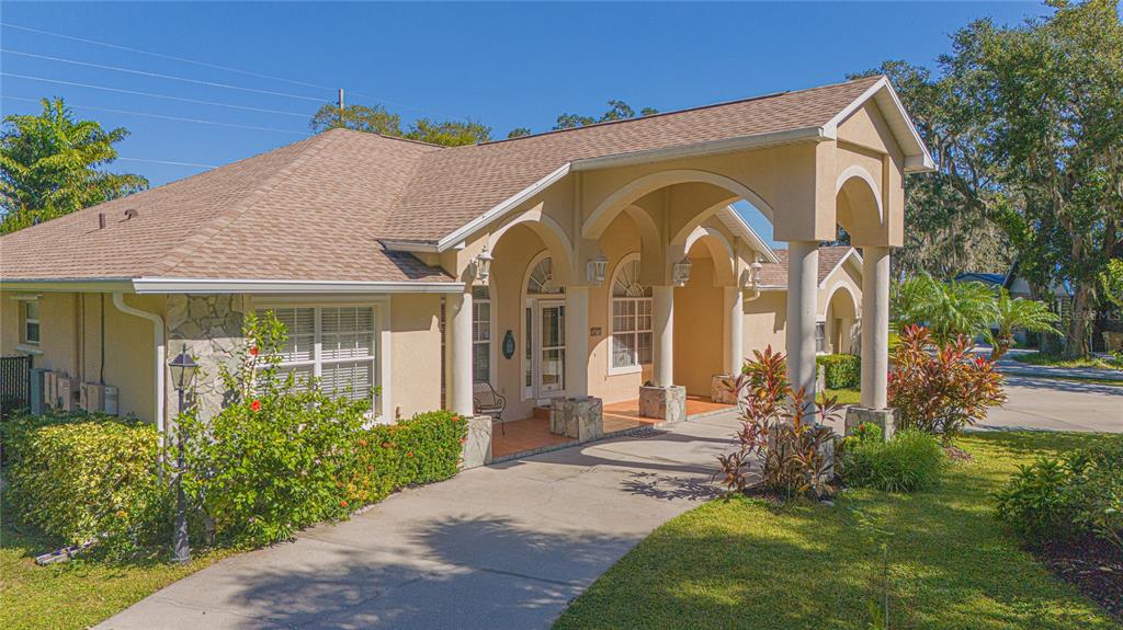 A tan house with a large arched covered entryway and a paved driveway — 4735 CHELSEA COURT, KISSIMMEE, FL