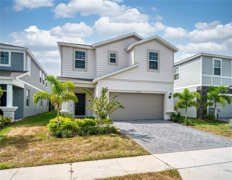 A two-story suburban house with beige siding, a stucco facade, and a two-car garage — 3436 LILAC WAY, DAVENPORT, FL