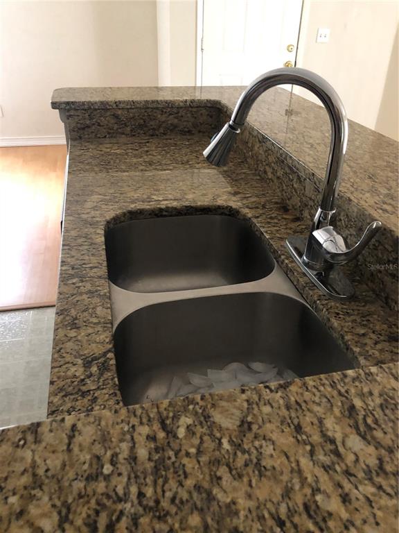 A stainless steel double-basin sink with a chrome faucet set in a granite countertop — 486 N PIN OAK PLACE UNIT 206, LONGWOOD, FL