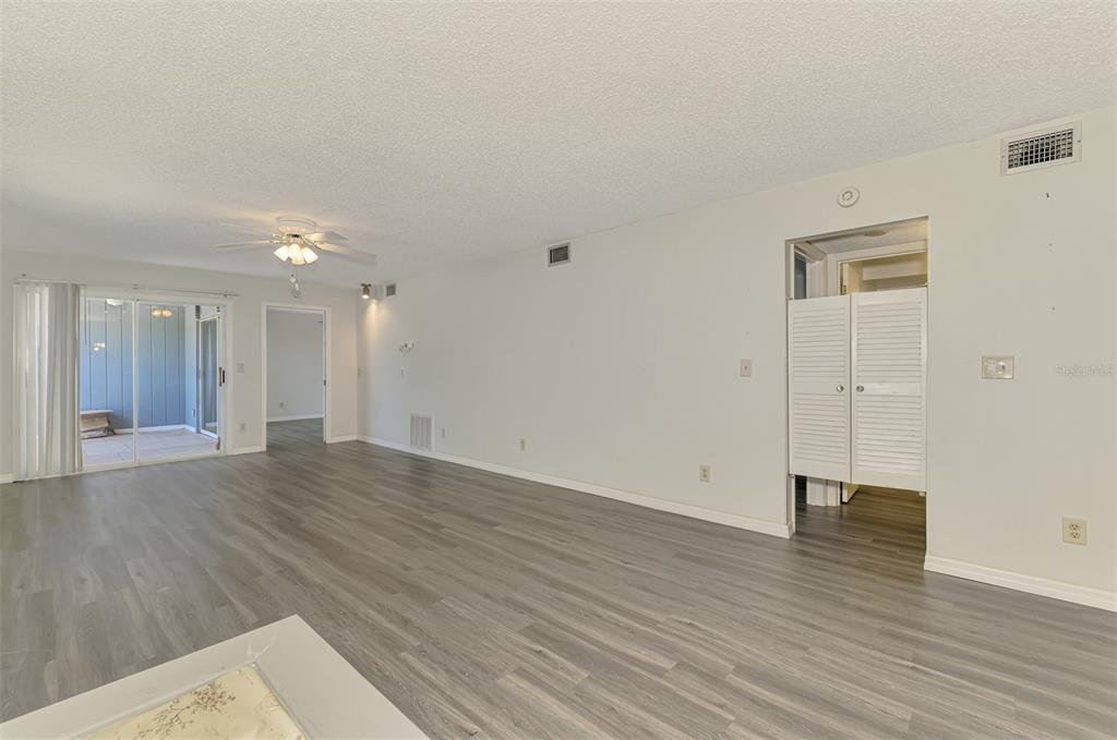 A spacious living room features light gray wood-look flooring, white walls, and a sliding glass door — 200 ROTONDA BOULEVARD W UNIT A2, ROTONDA WEST, FL