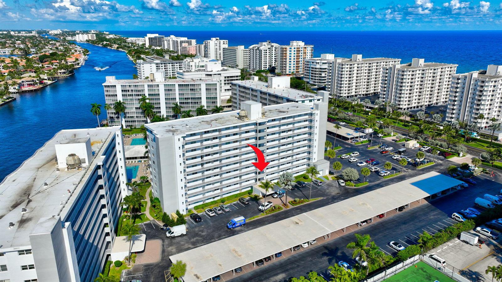 An aerial view shows a multi-story apartment building with a parking lot and nearby waterway — 3300 S Ocean Boulevard # c, Highland Beach FL 33487, HIGHLAND BEACH, FL