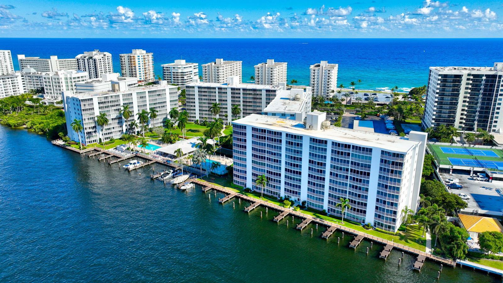 An aerial view shows multiple white apartment buildings situated along a waterfront with boat docks — 3300 S Ocean Boulevard # c, Highland Beach FL 33487, HIGHLAND BEACH, FL
