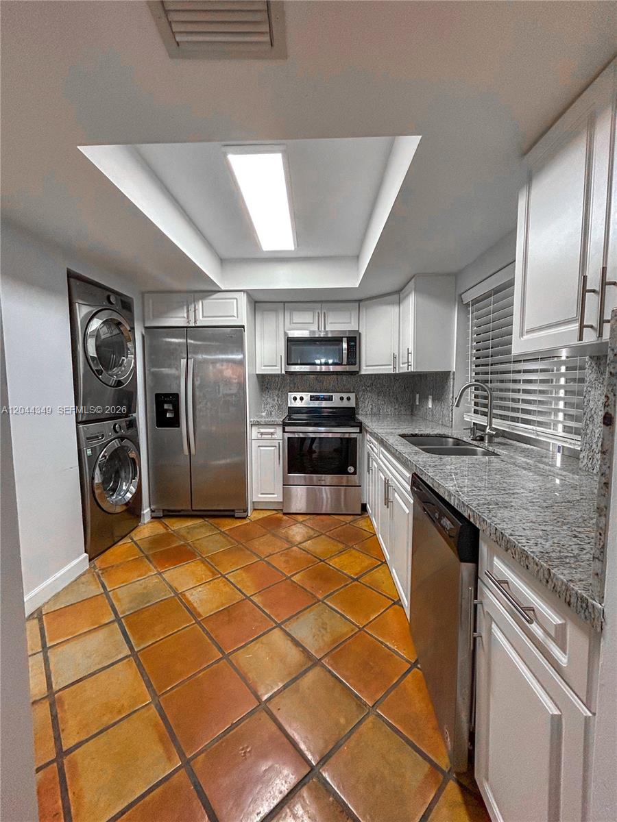 A kitchen features white cabinets, granite countertops, stainless steel appliances, and terracotta tile flooring — 14970 SW 48th Ter # 27G, Miami FL 33185, MIAMI, FL