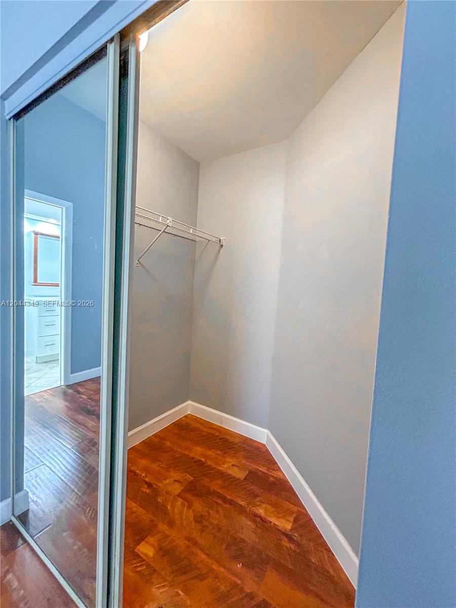 A walk-in closet features light blue walls, wood flooring, and a wire shelf — 14970 SW 48th Ter # 27G, Miami FL 33185, MIAMI, FL