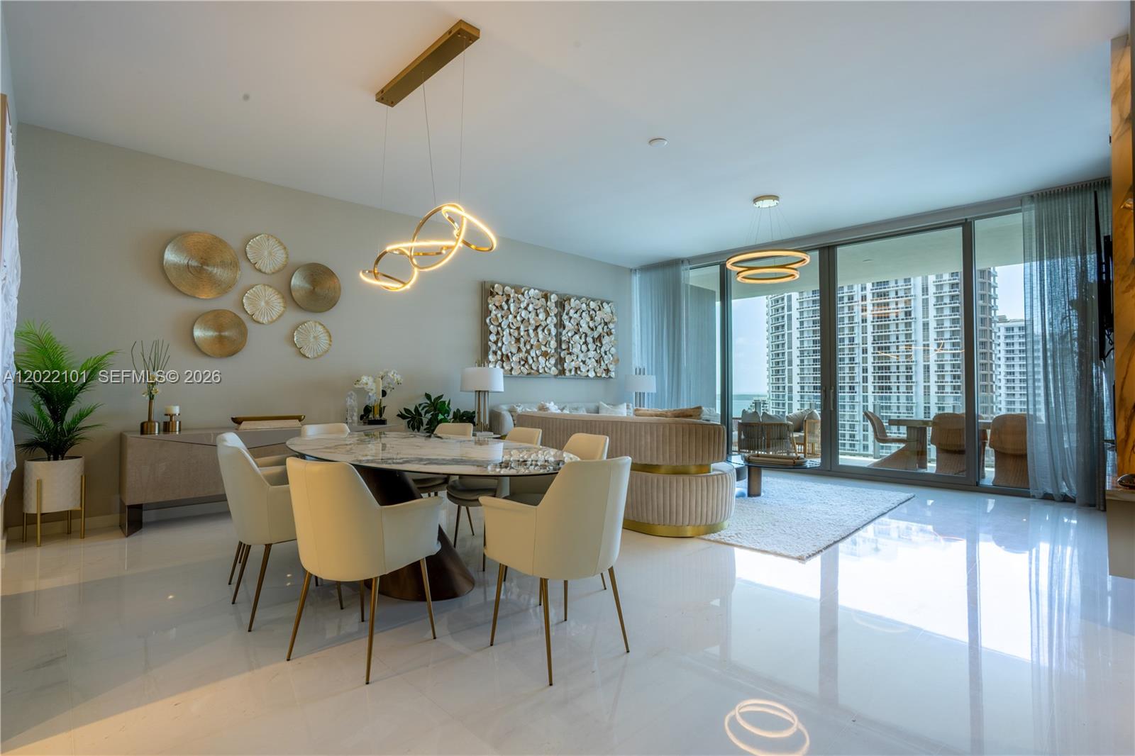 A modern dining and living area features a marble table, gold accents, and floor-to-ceiling windows — 300 Biscayne Boulevard Way # 2203C, Miami FL 33131, MIAMI, FL