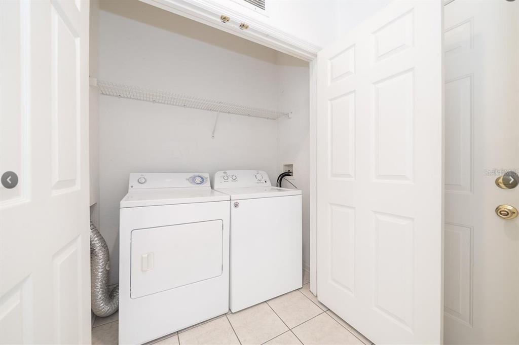 A laundry closet with a white washer and dryer, tiled floor, and wire shelving — 6166 STEVENSON DRIVE UNIT 302, ORLANDO, FL