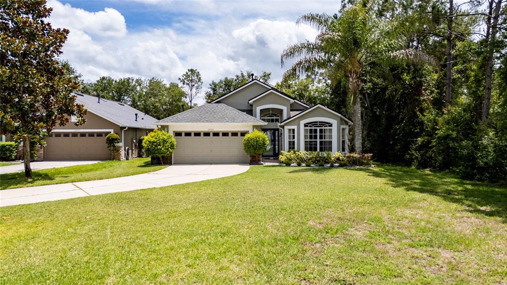 A single-story suburban house with a two-car garage, a palm tree, and a grassy lawn — 10966 ELIOTTI STREET, ORLANDO, FL