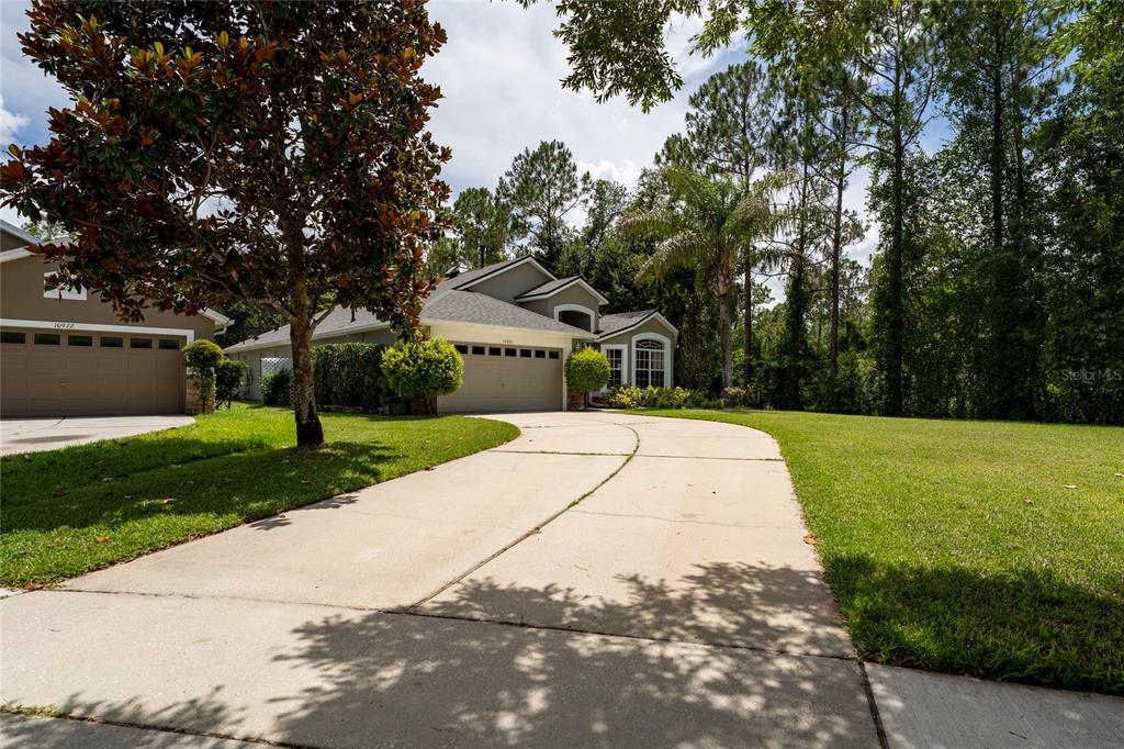 A concrete driveway leads to the garage of a single-story house with a lawn — 10966 ELIOTTI STREET, ORLANDO, FL
