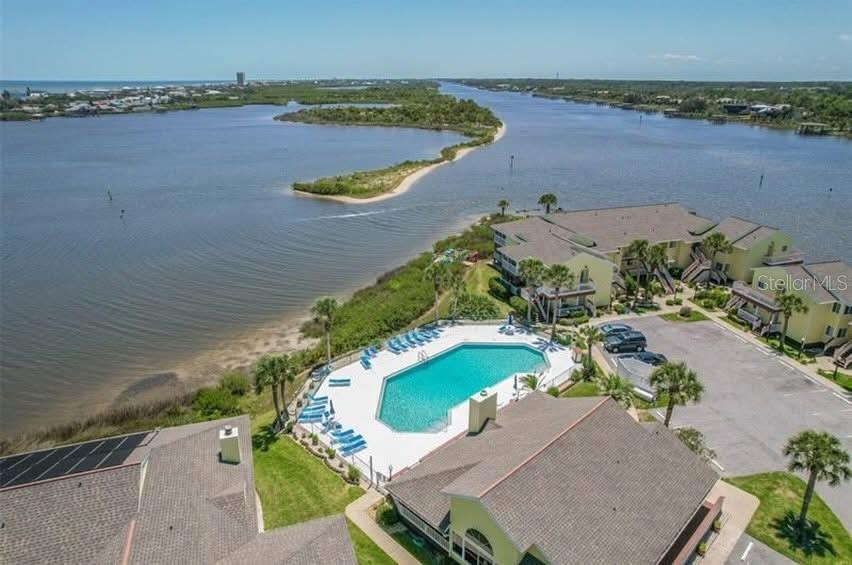 An aerial view shows a swimming pool next to waterfront residential buildings and a parking lot — 1003 OCEAN MARINA DRIVE UNIT 1003, FLAGLER BEACH, FL