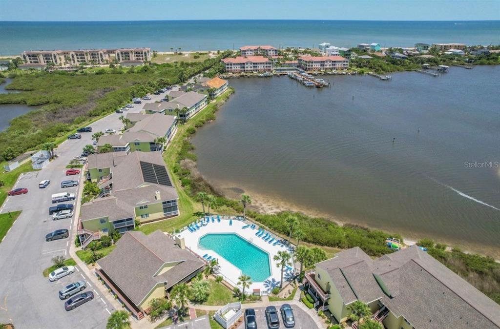 An aerial view shows a waterfront condominium complex with a swimming pool and parking lot — 1003 OCEAN MARINA DRIVE UNIT 1003, FLAGLER BEACH, FL