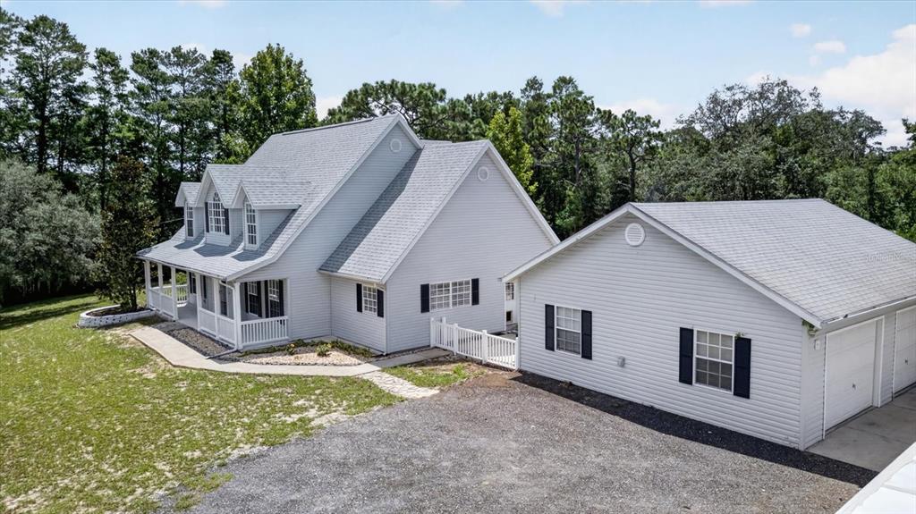 An exterior view of a light gray house with a white porch and detached garage — 34244 RIDGE MANOR BOULEVARD, DADE CITY, FL