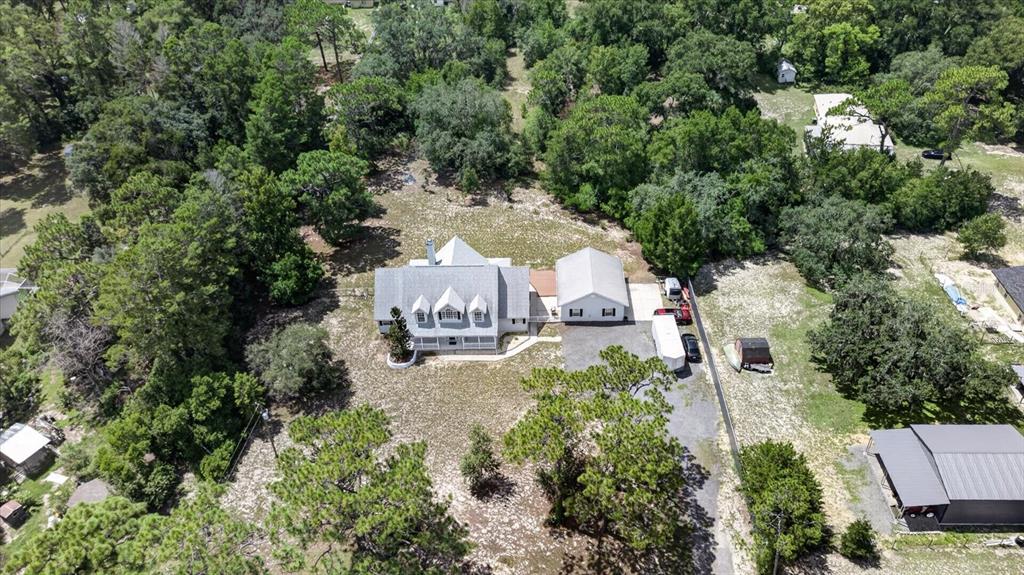 An aerial view shows a house with a detached garage surrounded by trees and grass — 34244 RIDGE MANOR BOULEVARD, DADE CITY, FL