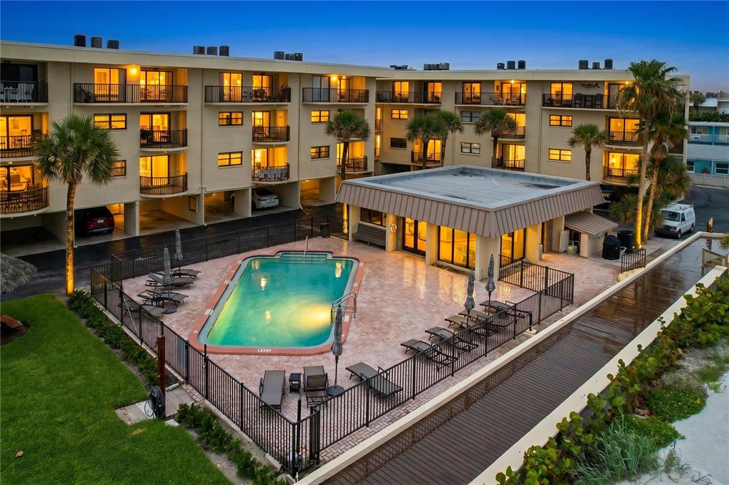 An exterior view of a multi-story apartment building with a swimming pool and patio area — 3500 GULF BOULEVARD UNIT 203, BELLEAIR BEACH, FL