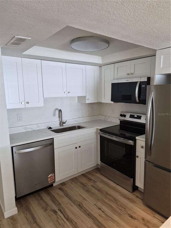 A kitchen with white cabinets, stainless steel appliances, and light-colored countertops — 8151 BLIND PASS ROAD UNIT 6, ST PETE BEACH, FL