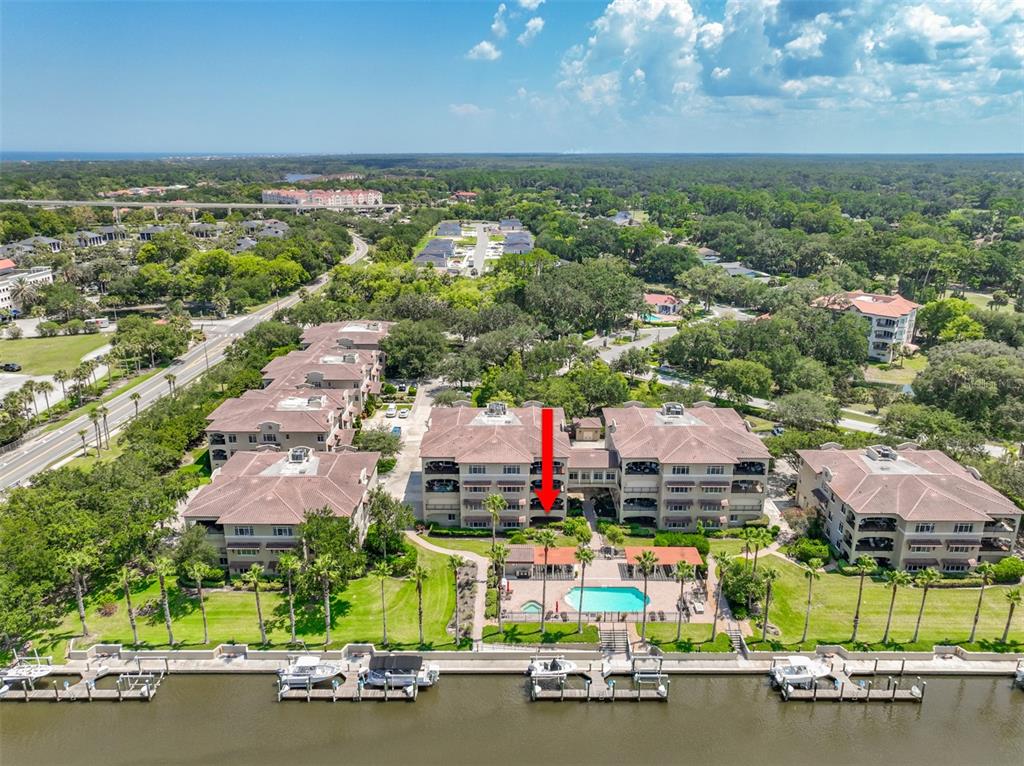 An aerial view shows a multi-story apartment complex with a swimming pool and boat docks — 106 CLUB HOUSE DRIVE UNIT 106, PALM COAST, FL