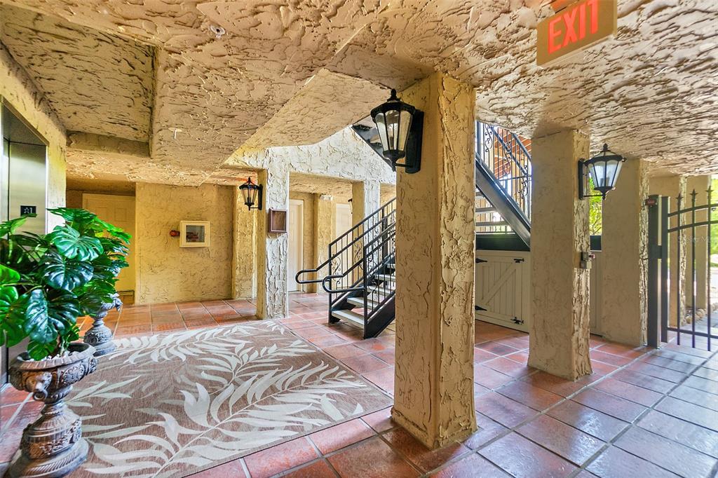 A covered outdoor entryway features textured walls, tile flooring, a decorative rug, and a staircase — 106 CLUB HOUSE DRIVE UNIT 106, PALM COAST, FL