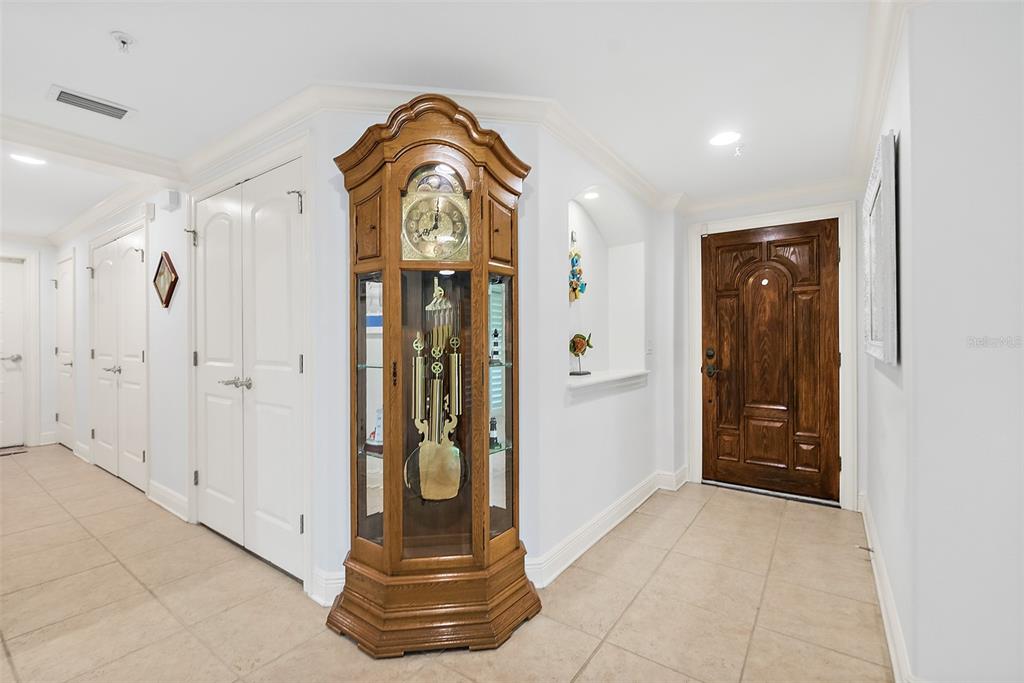 A wooden grandfather clock stands in a tiled entryway near a dark wood front door — 106 CLUB HOUSE DRIVE UNIT 106, PALM COAST, FL