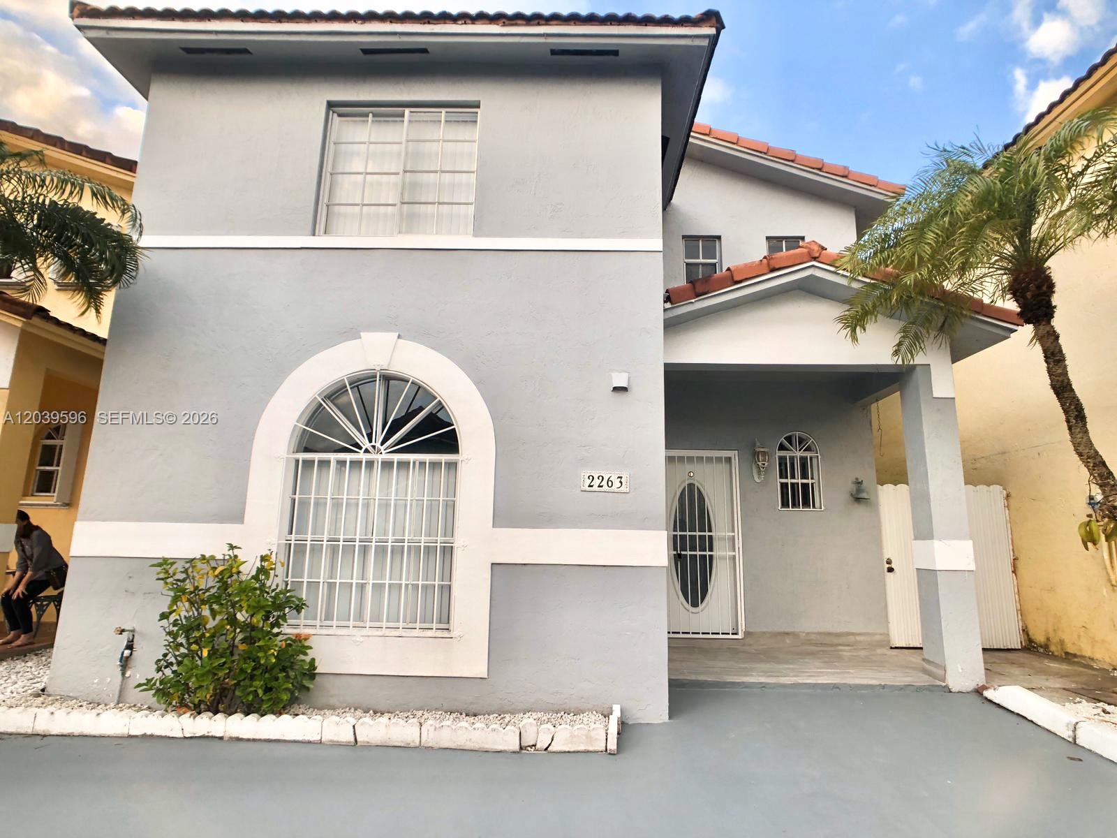 A two-story gray house features a white-trimmed arched window, a covered porch, and a palm tree — 7211 W 24th Ave # 2263, Hialeah FL 33016, HIALEAH, FL