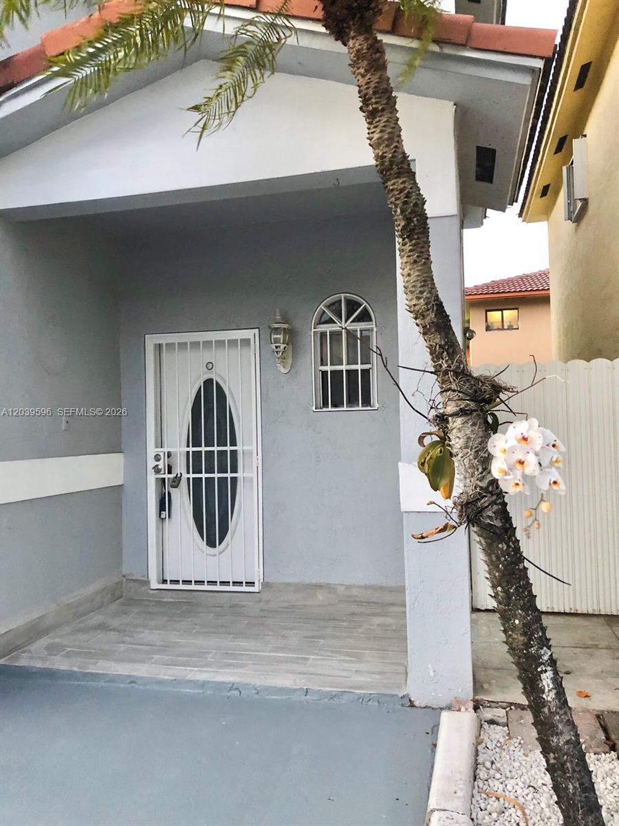 The exterior of a house features a gray facade, a white security door, and a palm tree — 7211 W 24th Ave # 2263, Hialeah FL 33016, HIALEAH, FL