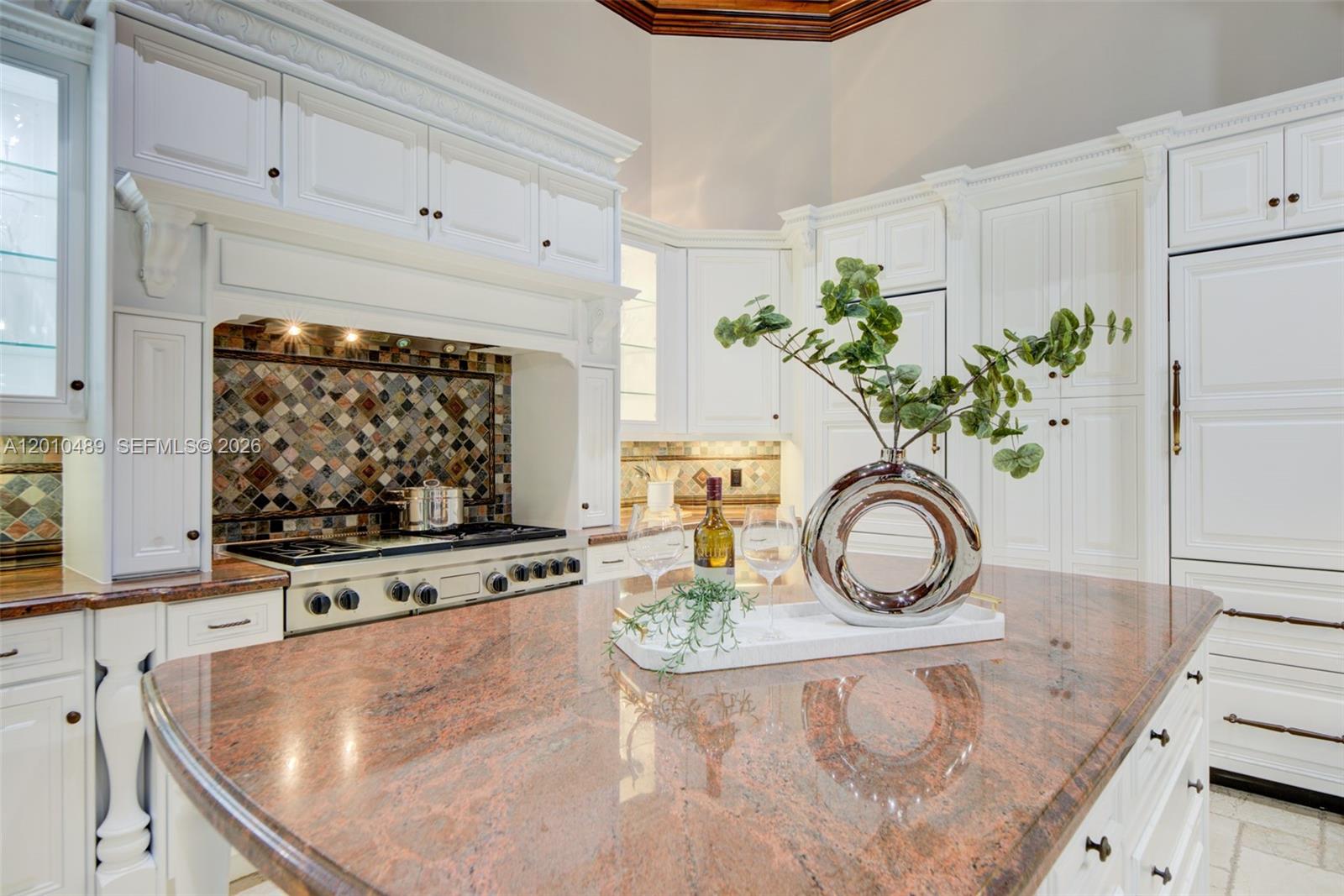 A kitchen features white cabinetry, a granite island countertop, and a tiled backsplash — 16740 Berkshire Ct, Southwest Ranches FL 33331, SOUTHWEST RANCHES, FL