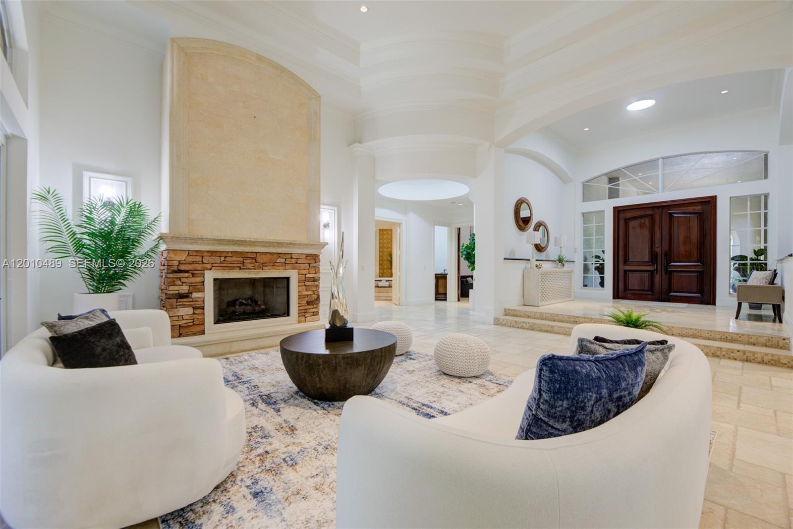 A spacious living room features a stone fireplace, white curved sofas, and a tiled floor — 16740 Berkshire Ct, Southwest Ranches FL 33331, SOUTHWEST RANCHES, FL
