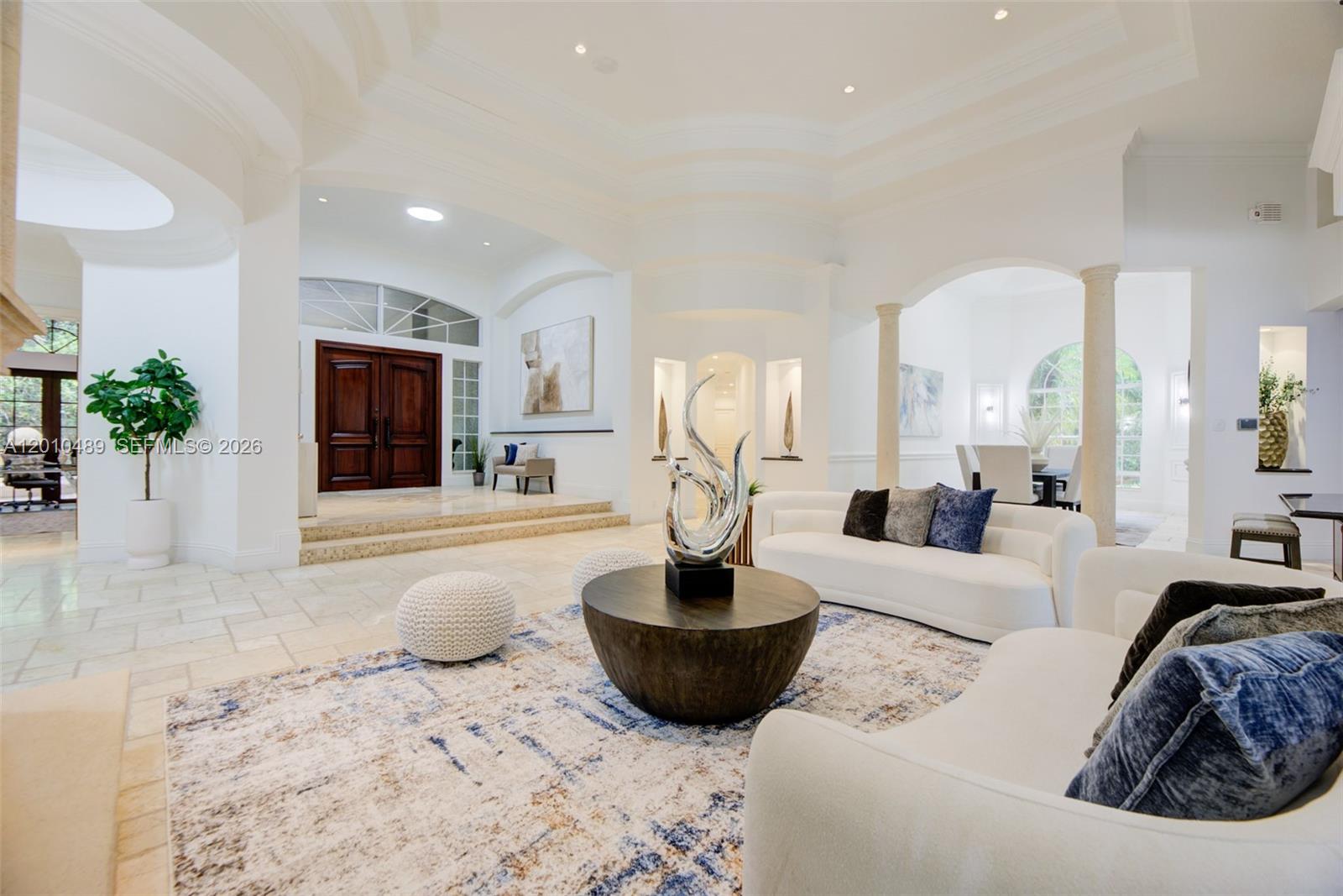 A spacious living room features white sofas, a round coffee table, and arched architectural details — 16740 Berkshire Ct, Southwest Ranches FL 33331, SOUTHWEST RANCHES, FL