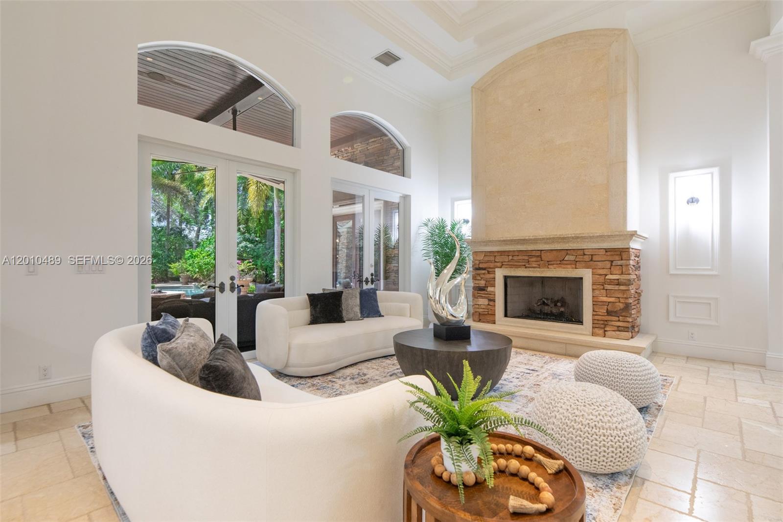 A living room features a stone fireplace, curved white sofas, and arched glass doors — 16740 Berkshire Ct, Southwest Ranches FL 33331, SOUTHWEST RANCHES, FL