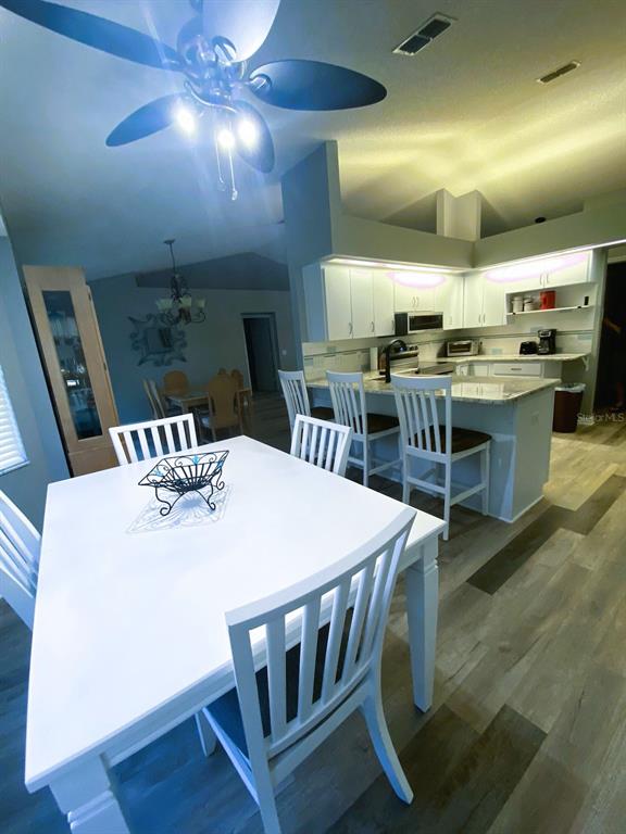 A dining area with a white table and chairs sits adjacent to a kitchen island — 111 LINDALE STREET, LAKELAND, FL