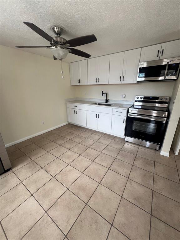 A kitchen features white cabinets, stainless steel appliances, a ceiling fan, and tiled flooring — 275 PINEAPPLE STREET UNIT B, ENGLEWOOD, FL