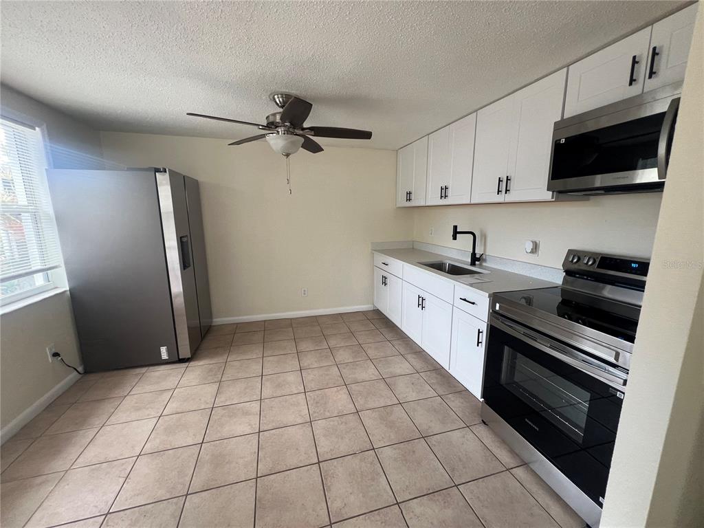 A kitchen with white cabinets, stainless steel appliances, and tan tile flooring — 275 PINEAPPLE STREET UNIT B, ENGLEWOOD, FL