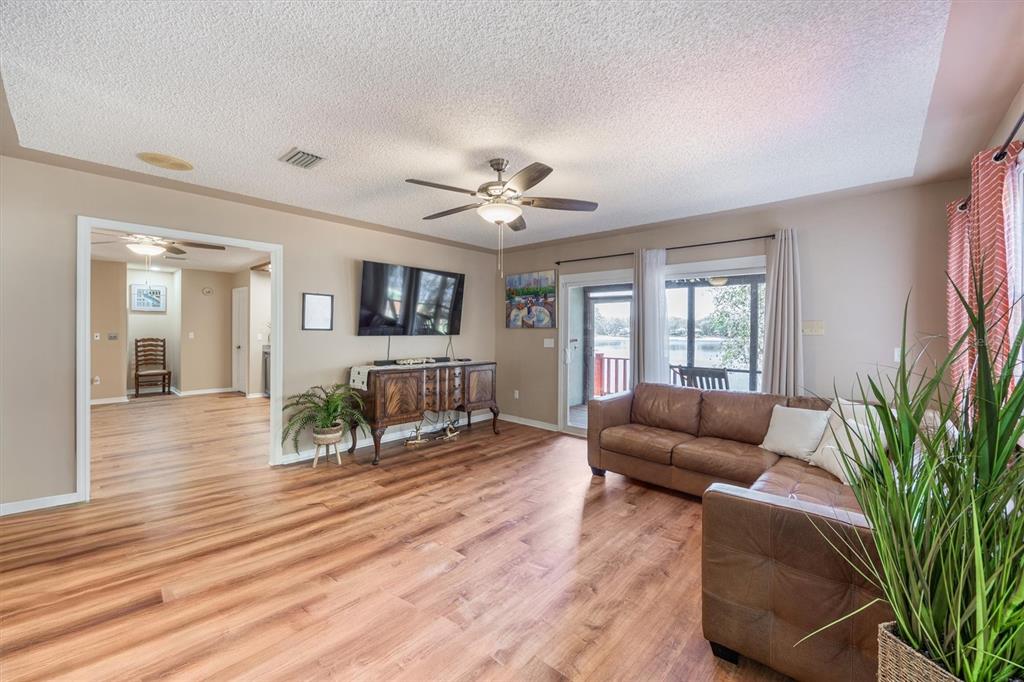 A living room with wood-look flooring, a brown leather sectional, and a view of a lake — 111 KIRBY TRAIL, MELROSE, FL