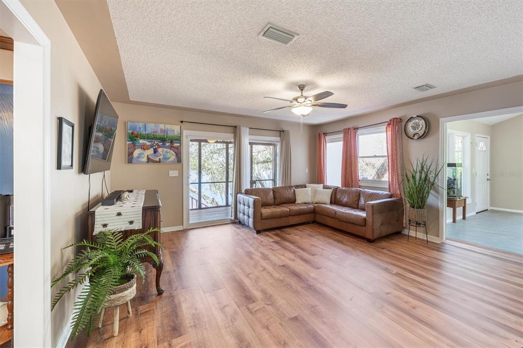 A living room features wood-look flooring, a brown leather sectional, and a ceiling fan — 111 KIRBY TRAIL, MELROSE, FL