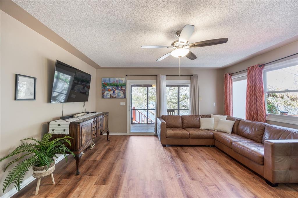 A living room features a brown leather sectional, wood-look flooring, and a sliding glass door — 111 KIRBY TRAIL, MELROSE, FL