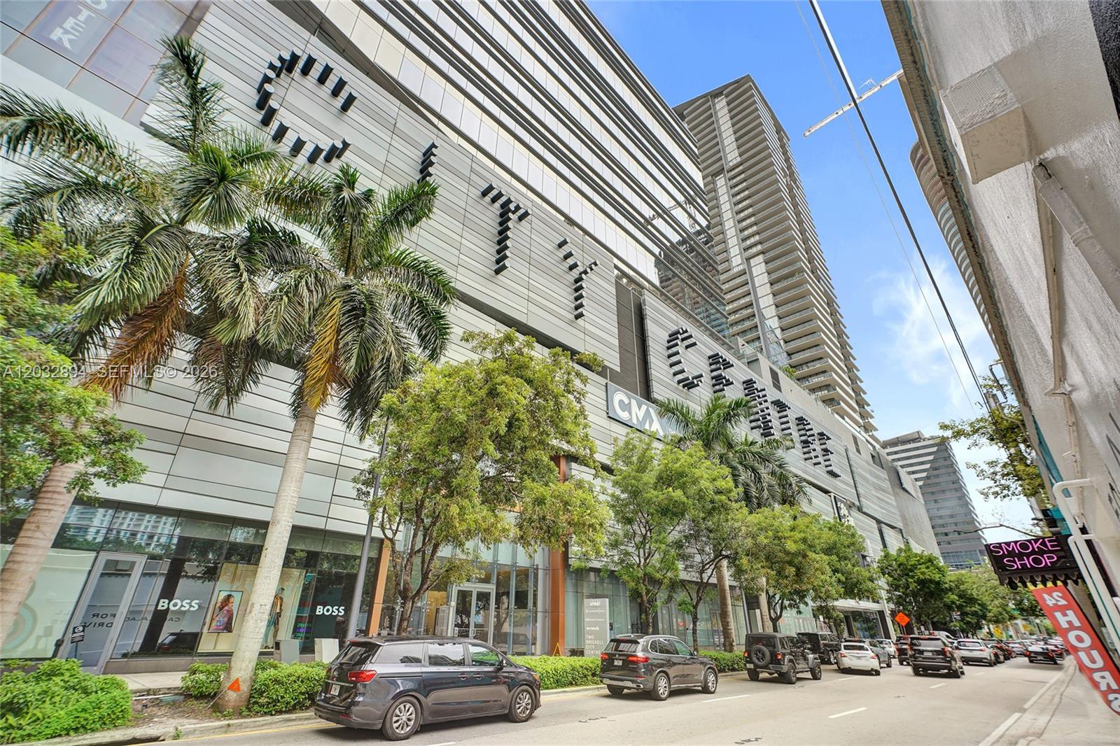 A low-angle exterior view of the Brickell City Centre shopping complex with palm trees and parked cars — 88 SW 7th St # 2210, Miami FL 33130, MIAMI, FL