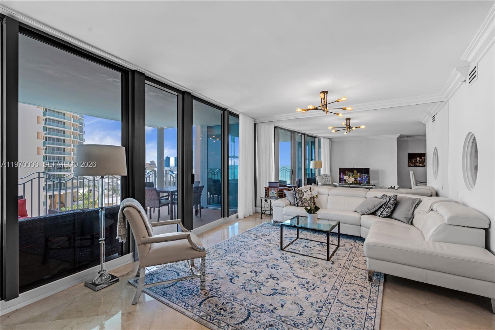 A living room features a white sectional sofa, a patterned rug, and floor-to-ceiling windows — 1500 Ocean Dr # 704, Miami Beach FL 33139, MIAMI BEACH, FL
