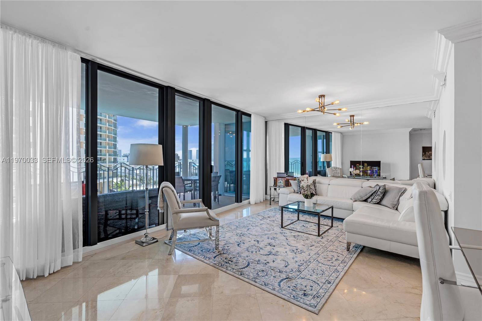 A bright living room features white furniture, a patterned area rug, and floor-to-ceiling windows — 1500 Ocean Dr # 704, Miami Beach FL 33139, MIAMI BEACH, FL
