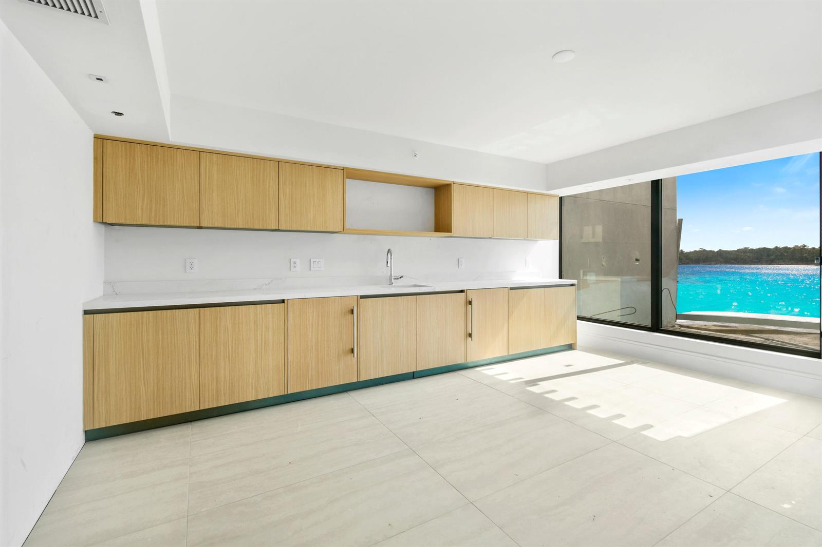 A modern kitchen with light wood cabinets, white countertops, and a view of the ocean — 12450 SE Crystal Cove Place # 13, Jupiter FL 33469, JUPITER, FL