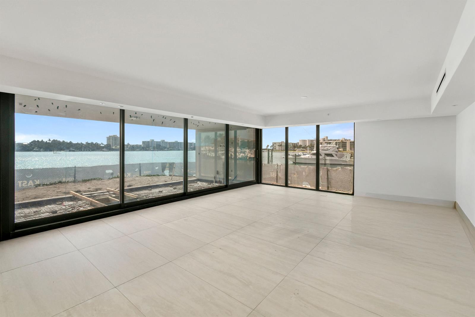 An empty room with large floor-to-ceiling windows overlooking a waterfront construction site — 12450 SE Crystal Cove Place # 13, Jupiter FL 33469, JUPITER, FL