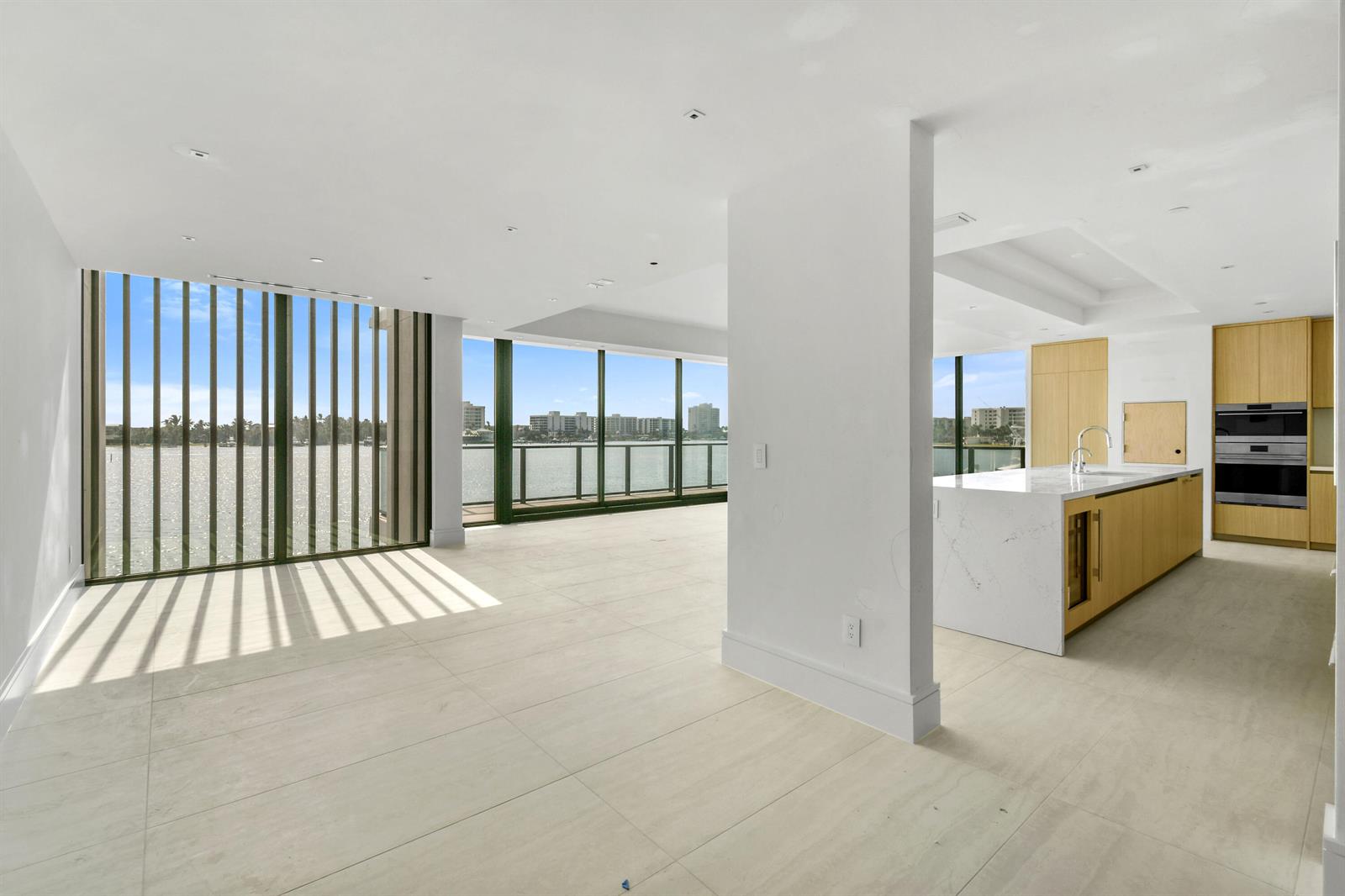 A modern open-plan kitchen and living area with floor-to-ceiling windows overlooking the water — 12450 SE Crystal Cove Place # 13, Jupiter FL 33469, JUPITER, FL