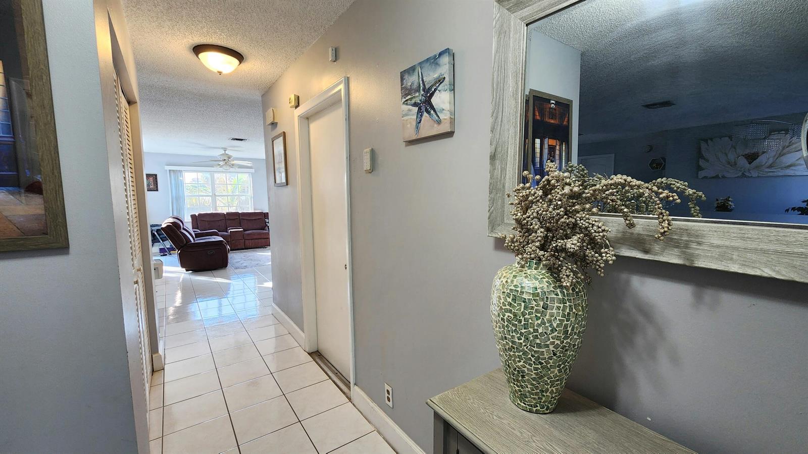 A hallway with tiled floors leads to a living room with a brown sofa set — 4209 Waverly Drive, West Palm Beach FL 33407, WEST PALM BEACH, FL