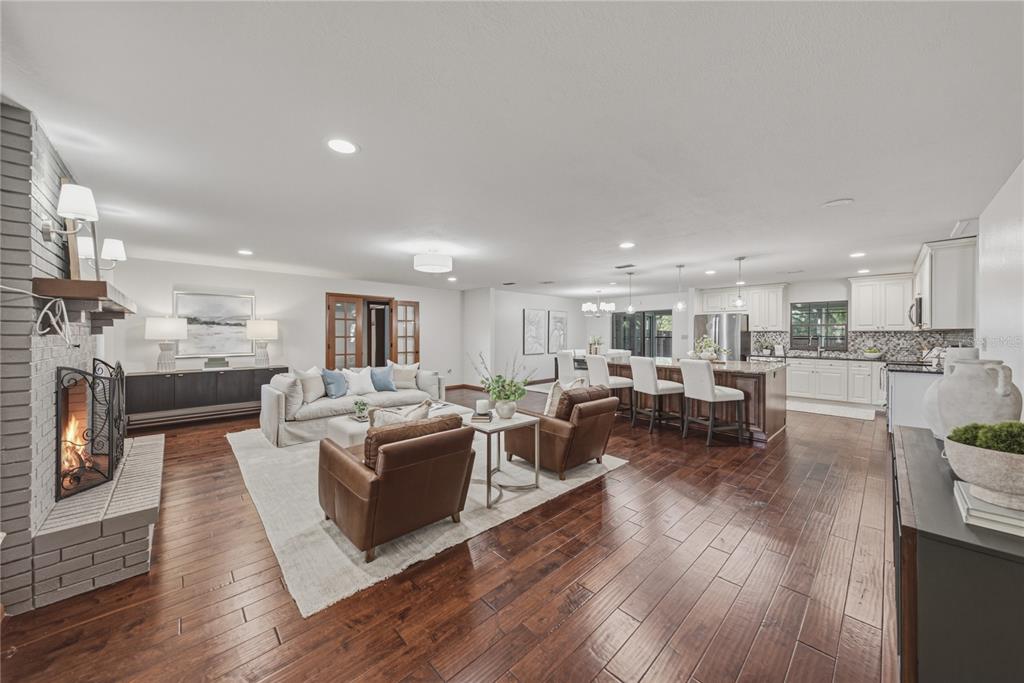 An open-concept living room and kitchen feature hardwood floors, a brick fireplace, and white cabinetry — 236 PINELLAS STREET, LAKELAND, FL
