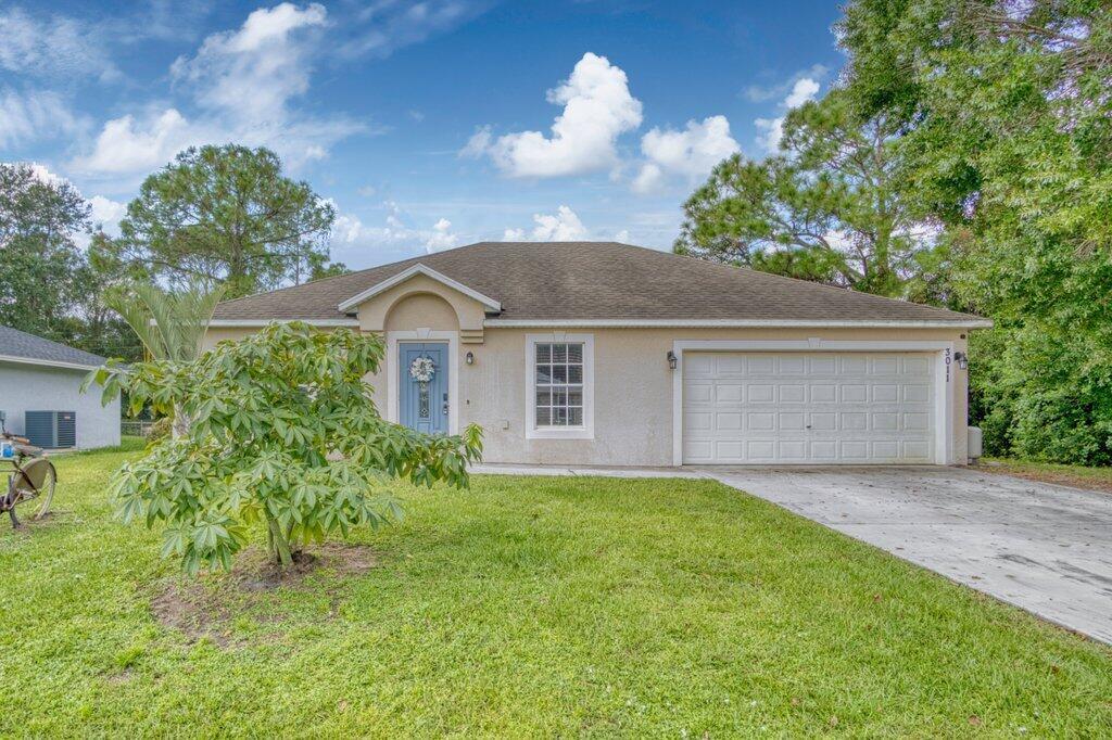 A single-story house with a light-colored stucco exterior, a blue front door, and a garage — 3011 NW 33rd Avenue, Okeechobee FL 34972, OKEECHOBEE, FL